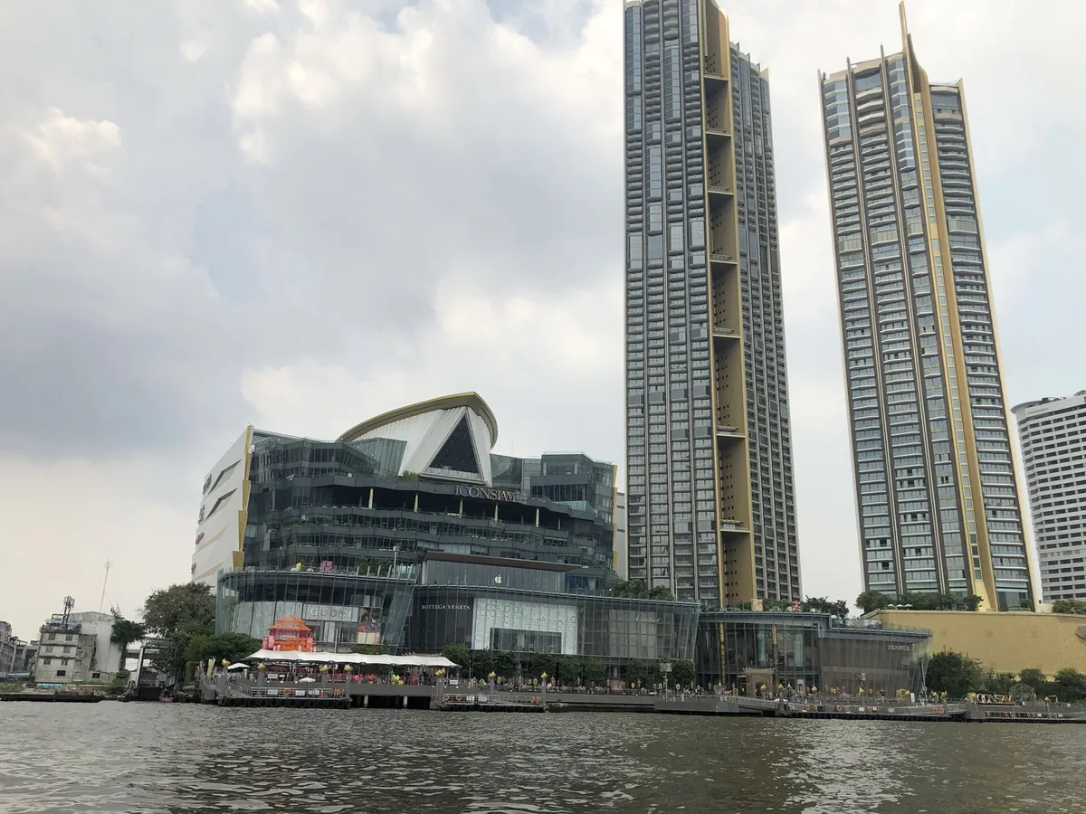 從昭披耶河上看向西岸的 ICONSIAM 購物中心與旁邊兩棟高層住宅，前景是河面