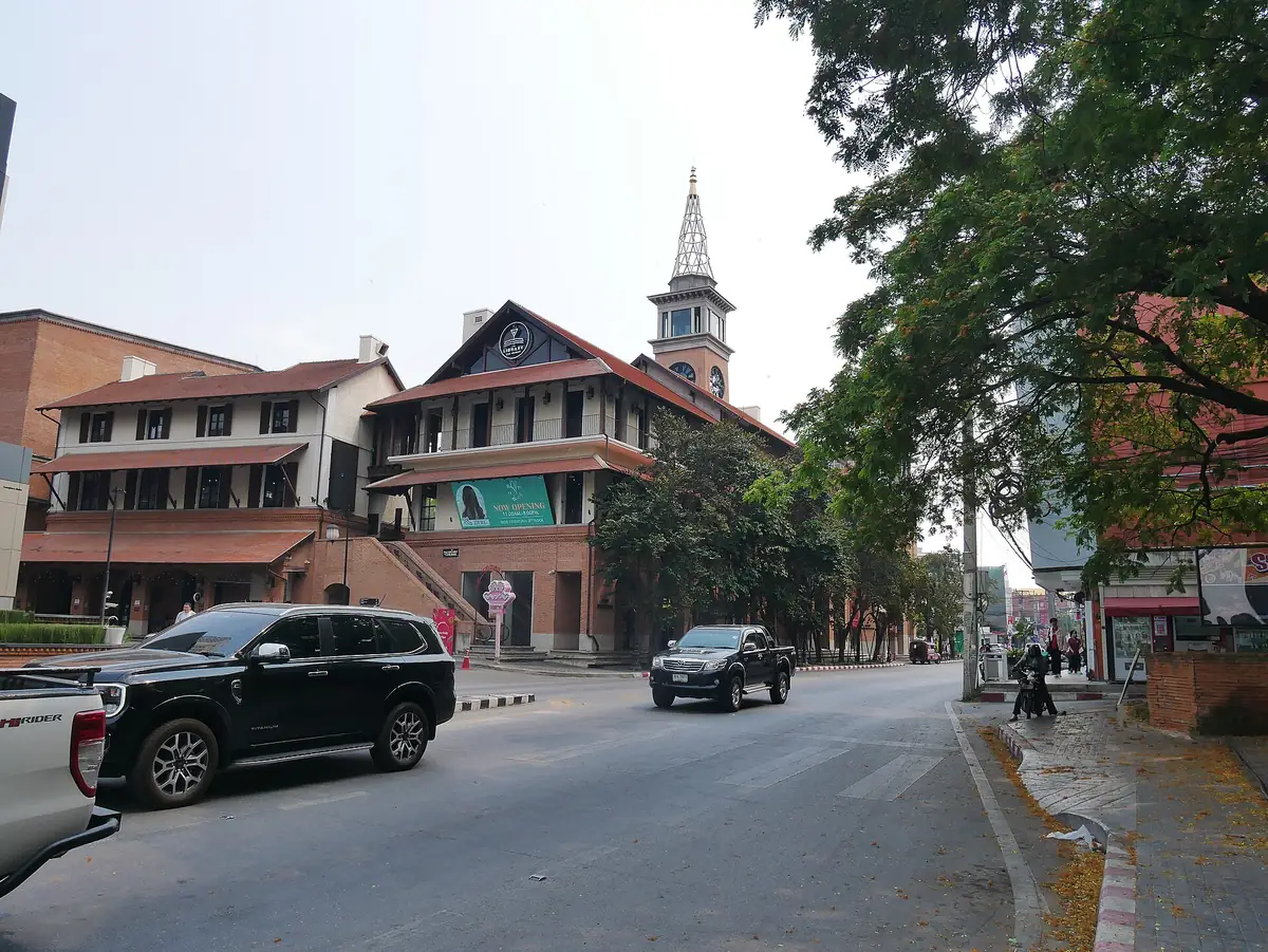 清邁尼曼路一帶的街景，路旁是紅磚屋頂的建築與一座鐘樓