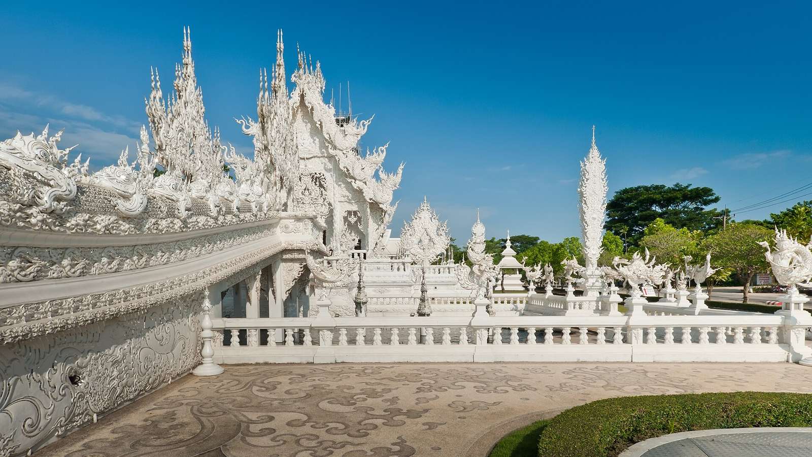 清萊白廟的白色雕塑寺院與長廊欄杆，藍天下細密的白色尖塔、那伽雕飾與白色迴廊連成一片