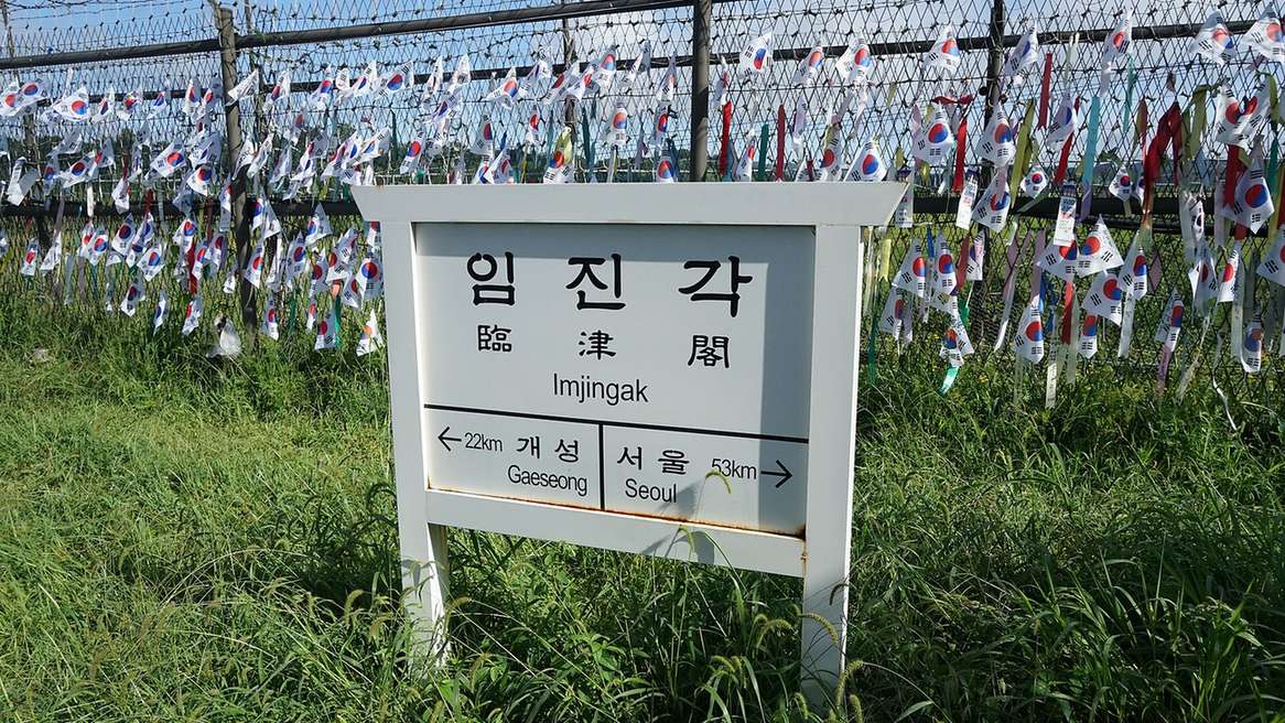 臨津閣園區的臨津閣指標牌，後方鐵絲網上掛滿小國旗與緞帶