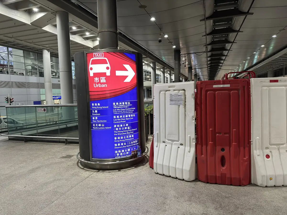 香港機場的士站旁的指示柱，上半紅底寫著市區 Urban，下半藍底列出可到達的區域