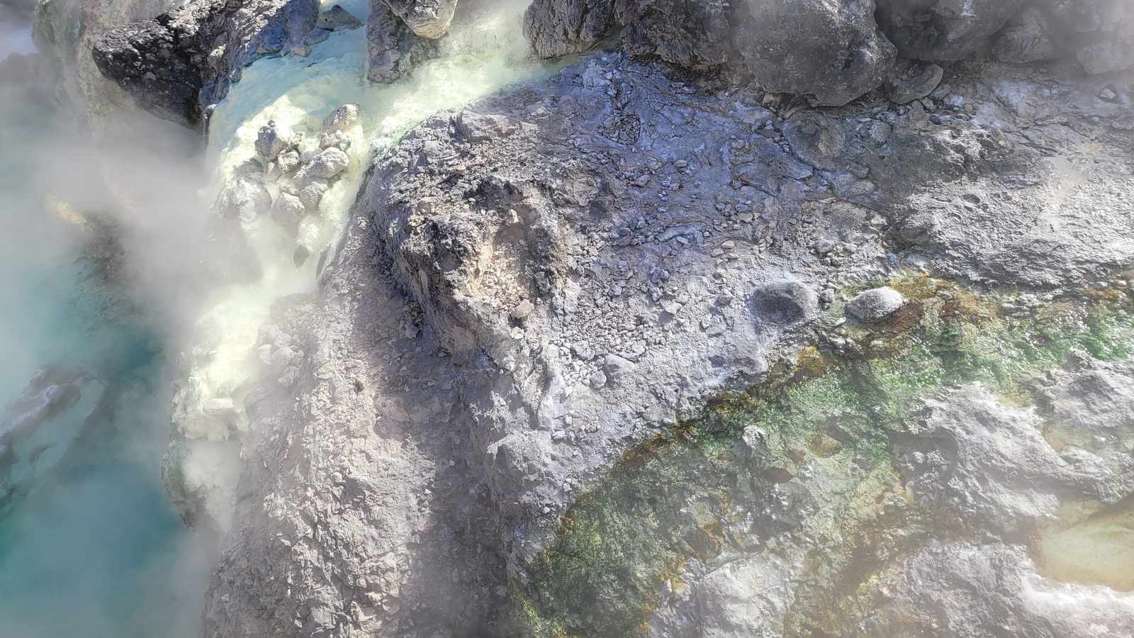 草津溫泉湯畑的木製導湯槽冒著白煙，四周是溫泉街的旅館與遊客