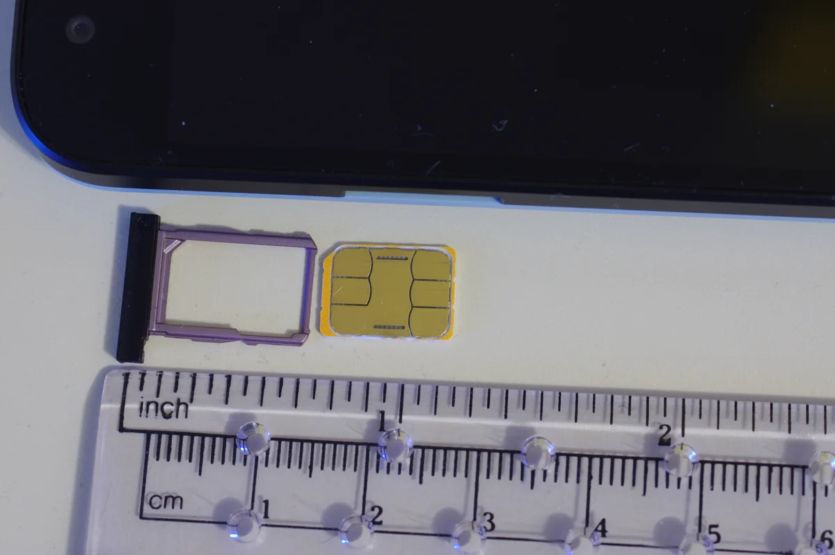 一張 nano SIM 卡與手機的 SIM 卡托盤放在尺旁邊，顯示實際大小
