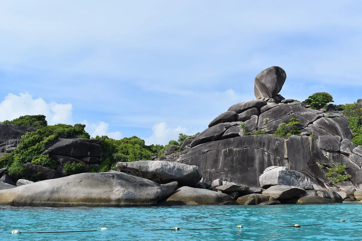 斯米蘭群島海面上堆疊的花崗岩巨石與上方的圓形巨岩,岩下是清澈的藍綠色海水
