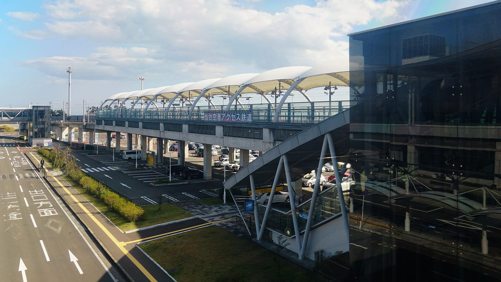 仙台空港站的高架月台與連絡橋，橋側寫著仙台空港アクセス鉄道，右邊是航廈的玻璃帷幕