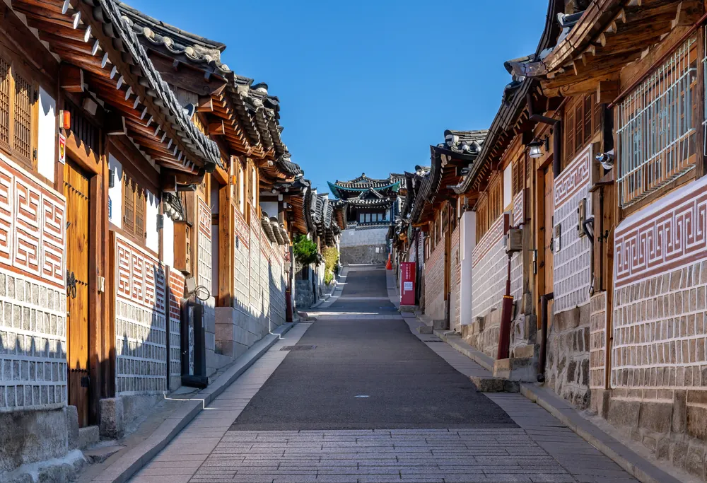 北村路 11 街兩側的韓屋屋瓦與石牆，藍天下的上坡巷道