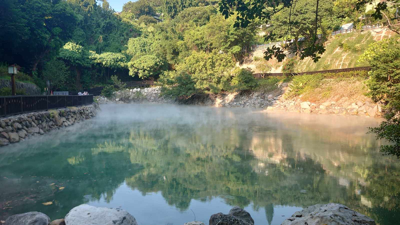 Steam rising off the jade-green pool of Thermal Valley in Beitou, with the boardwalk and hillside behind