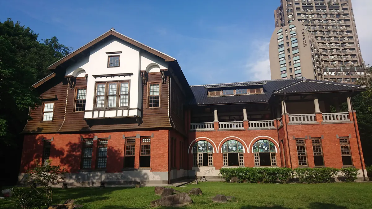 芝生の向こうに建つ煉瓦と木造の北投温泉博物館。1913 年建造の旧北投公共浴場