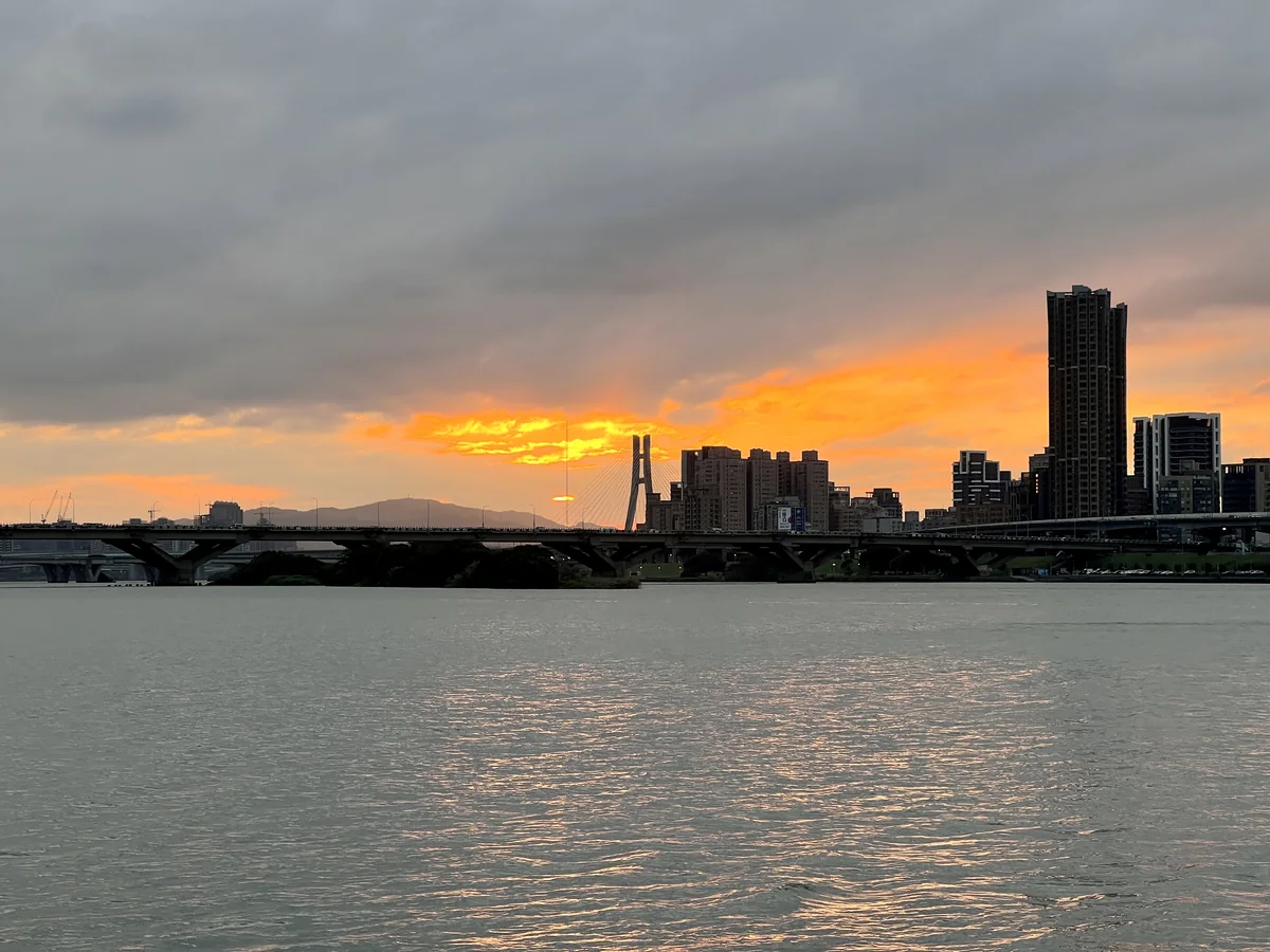 Orange sunset clouds over the Tamsui River and the Sanchong skyline, seen from Dadaocheng Wharf