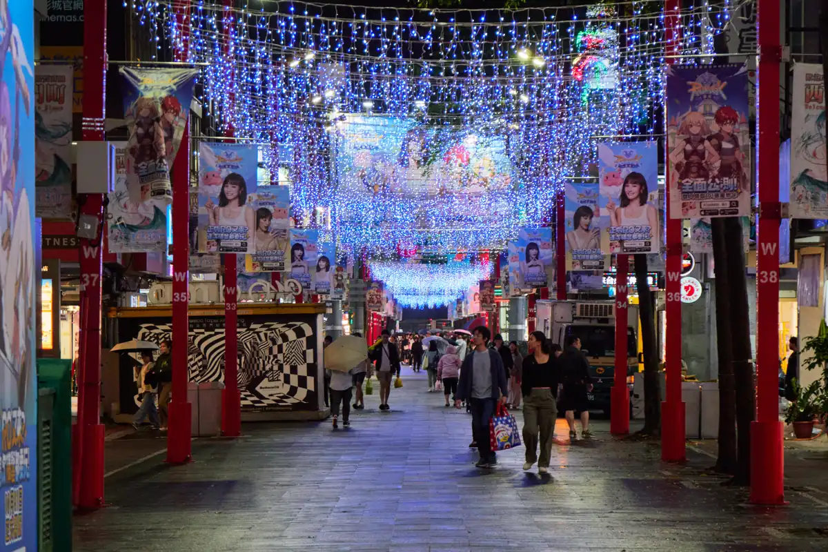 Evening crowd on Ximending's main pedestrian street under strings of blue lights and anime banners