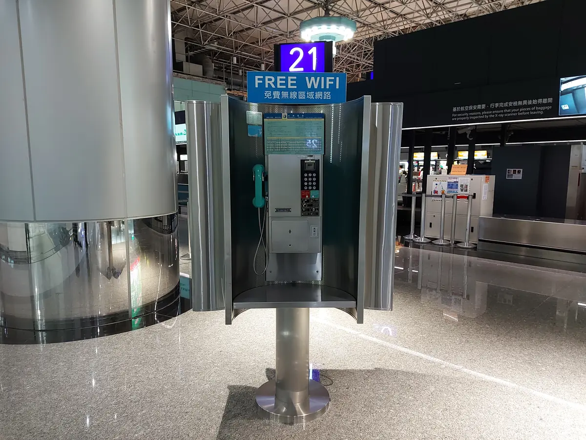 A Chunghwa Telecom payphone under a FREE WIFI sign in a Taoyuan Airport terminal hall