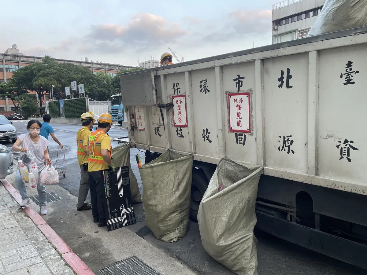 ペットボトルを持って台北市の資源回収車へ向かう住民と、横で待つヘルメット姿の作業員