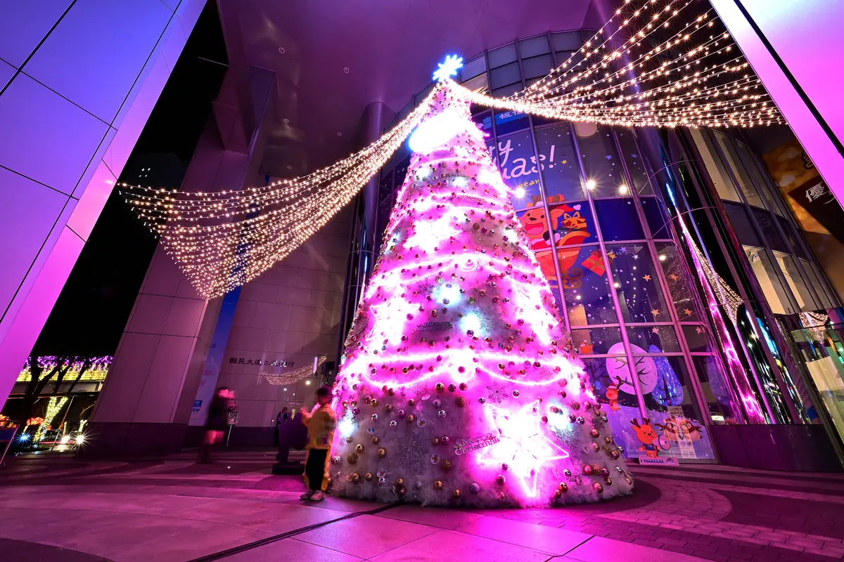 Pink-lit Christmas tree and strings of fairy lights outside a building at Christmasland in New Taipei City