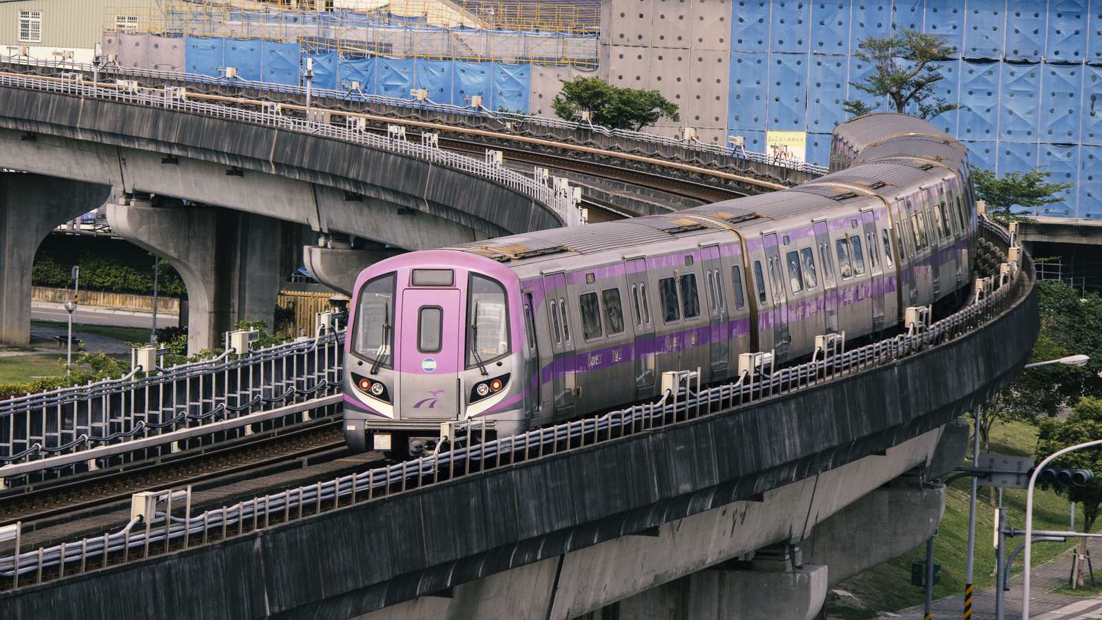 A purple Taoyuan Airport MRT Express train leaving New Taipei Industrial Park station on the elevated line toward the airport
