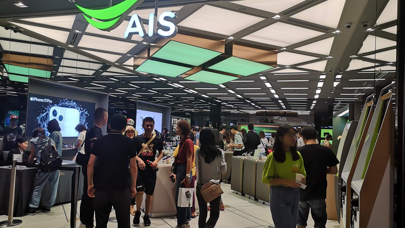 Customers queue at the counter under the green AIS sign inside the AIS shop at Bangkok's ICONSIAM mall