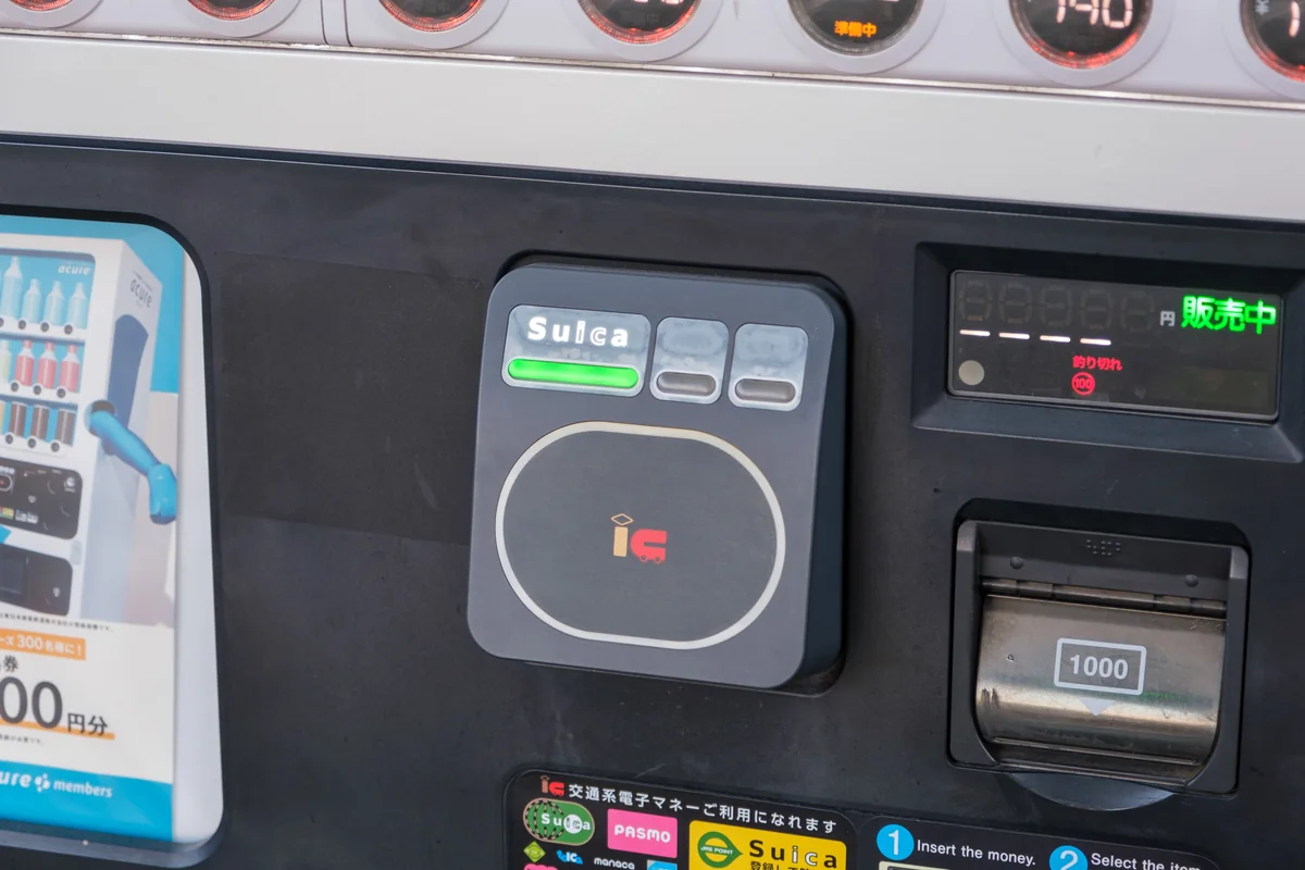 A Suica card held against a vending machine’s contactless payment reader