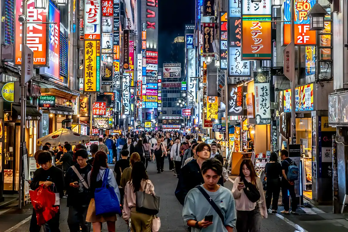A Shinjuku street at night, with crowds beneath neon signs