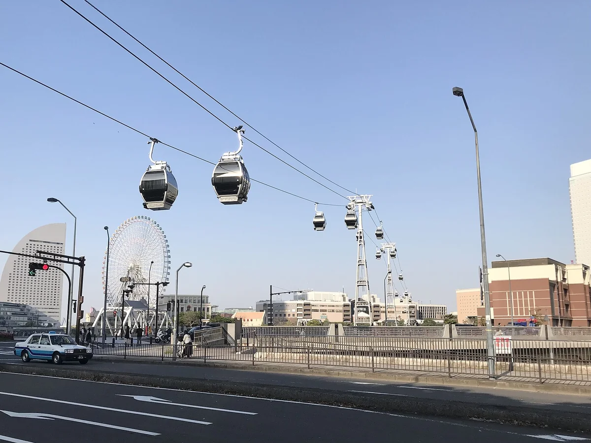 YOKOHAMA AIR CABIN 的纜車車廂與支柱，背景是港未來的摩天輪